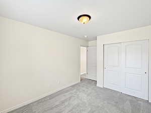 Unfurnished bedroom with carpet, baseboards, and a closet