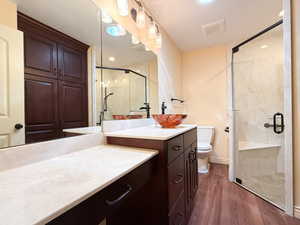 Bathroom featuring vanity, a stall shower, wood finished floors, toilet, and baseboards
