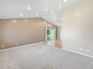 Unfurnished living room featuring carpet floors, vaulted ceiling, baseboards, and recessed lighting