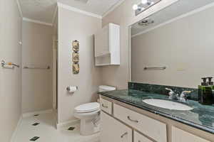 Bathroom with a textured ceiling, vanity, ornamental molding, light tile patterned floors, and a stall shower