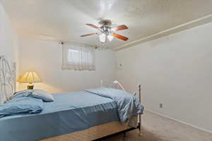 Bedroom with carpet floors, a textured ceiling, and ceiling fan