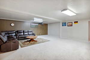 Carpeted living area with a textured ceiling, baseboards, and wooden walls