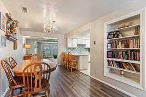 Dining area featuring dark wood-style floors, a textured ceiling, and a chandelier
