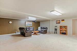 Living room with carpet, a textured ceiling, and a baseboard heating unit