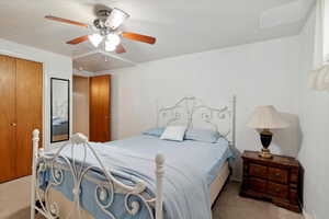 Carpeted bedroom featuring ceiling fan and a closet