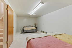 Carpeted bedroom featuring baseboard heating and a textured ceiling