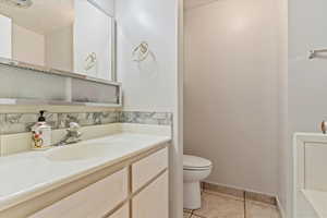 Half bathroom with a textured ceiling, light tile patterned floors, vanity, and decorative backsplash