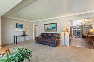 Carpeted living room featuring a textured ceiling, a chandelier, a wall unit AC, and tile patterned floors