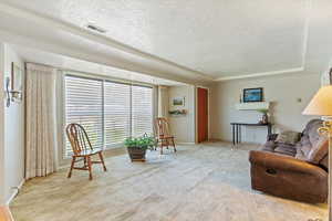 Living area featuring light colored carpet and a textured ceiling
