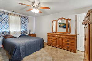 Bedroom featuring light carpet, a ceiling fan, and a textured ceiling