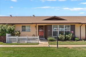 Ranch-style home with a shingled roof, brick siding, and covered porch