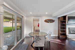 Dining space with baseboards, recessed lighting, dark wood-type flooring, crown molding, and a brick fireplace