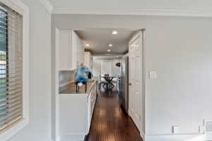 Corridor with dark wood finished floors, ornamental molding, and recessed lighting