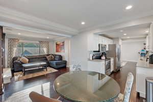 Dining space with dark wood-type flooring, crown molding, recessed lighting, and baseboards