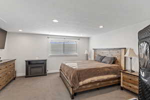 Primary Bedroom with light colored carpet, recessed lighting, baseboards, and a fireplace