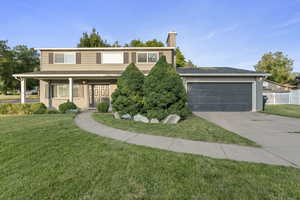 Traditional-style house featuring concrete driveway, brick siding, a chimney, an attached garage, and roof with shingles