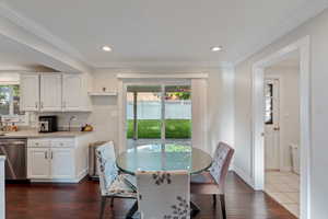 Dining room featuring dark wood finished floors, crown molding, baseboards, and recessed lighting