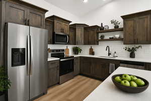 Kitchen with stainless steel appliances, a sink, dark brown cabinets, light countertops, and recessed lighting