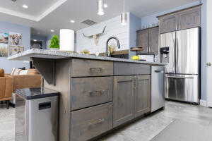 Kitchen featuring stainless steel appliances, open floor plan, hanging light fixtures, a kitchen island with sink, and a sink