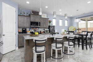 Kitchen with stainless steel microwave, light countertops, recessed lighting, a kitchen bar, and an island with sink