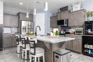 Kitchen featuring stainless steel appliances, a kitchen breakfast bar, decorative light fixtures, backsplash, and a kitchen island with sink