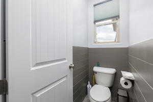 Bathroom with toilet, a wainscoted wall, and tile walls