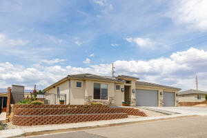 View of front facade with an attached garage, driveway, and stucco siding