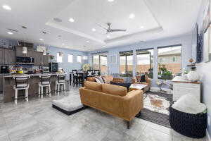 Living area featuring a raised ceiling, recessed lighting, and ceiling fan