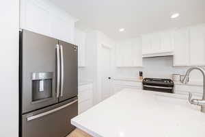 Kitchen featuring appliances with stainless steel finishes, a sink, white cabinets, recessed lighting, and light stone countertops