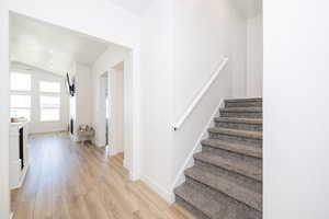 Staircase with vaulted ceiling, wood finished floors, and baseboards