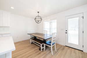 Dining room with light wood-type flooring, a chandelier, baseboards, and recessed lighting