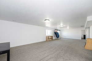 Basement with light colored carpet, baseboards, and a textured ceiling