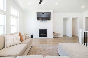 Living area featuring wood finished floors, recessed lighting, a ceiling fan, a glass covered fireplace, and baseboards