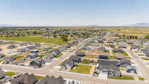 Aerial view of property and surrounding area featuring a mountainous background and nearby suburban area