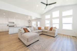 Living area featuring light wood-style flooring, recessed lighting, a ceiling fan, high vaulted ceiling, and baseboards