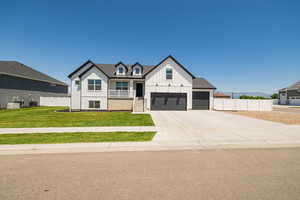 Modern farmhouse featuring board and batten siding, concrete driveway, a porch, central AC unit, and an attached garage