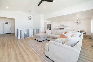 Living area with vaulted ceiling, light wood-style floors, a chandelier, ceiling fan, and recessed lighting
