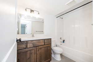 Full bath featuring tile patterned flooring, toilet, vanity, and washtub / shower combination