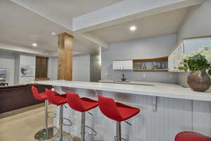 Kitchen featuring light countertops, a kitchen breakfast bar, white cabinets, a peninsula, and recessed lighting