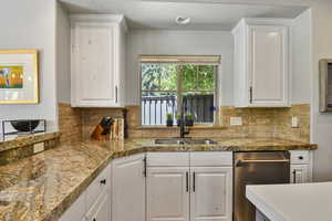 Kitchen with dishwasher, a sink, white cabinetry, backsplash, and a textured ceiling