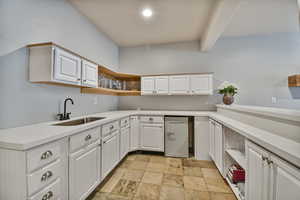 Kitchen with a sink, open shelves, light stone finish floors, and white cabinetry