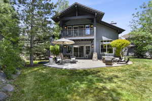 Back of house with a balcony, a chimney, a lawn, a patio area, and an outdoor hangout area