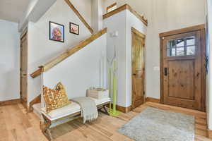 Foyer featuring baseboards, wood finished floors, and stairway