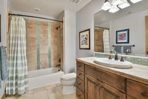 Full bathroom with shower / bath combo with shower curtain, vanity, tile patterned floors, toilet, and a skylight
