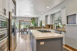 Kitchen featuring appliances with stainless steel finishes, a sink, light wood-type flooring, recessed lighting, and a textured ceiling