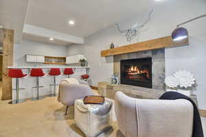 Living area featuring a tiled fireplace, carpet, recessed lighting, and baseboards
