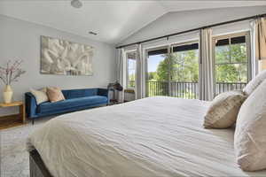 Carpeted bedroom with vaulted ceiling, access to exterior, and multiple windows