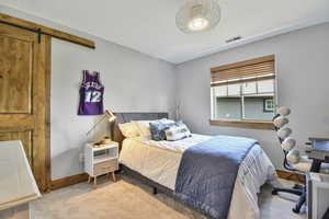 Carpeted bedroom with a barn door and baseboards