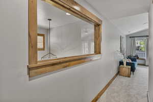 Corridor with carpet floors, lofted ceiling, plenty of natural light, and baseboards