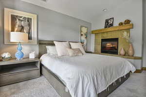 Bedroom featuring carpet flooring and a tile fireplace